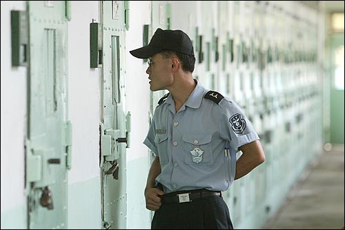 한 교도관이 시찰구를 통해 재소자들을 살펴보고 있다. 